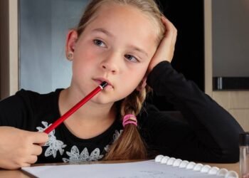 Garotinha perdida em pensamentos enquanto faz lição de casa