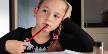 Garotinha perdida em pensamentos enquanto faz lição de casa