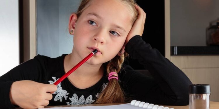 Garotinha perdida em pensamentos enquanto faz lição de casa