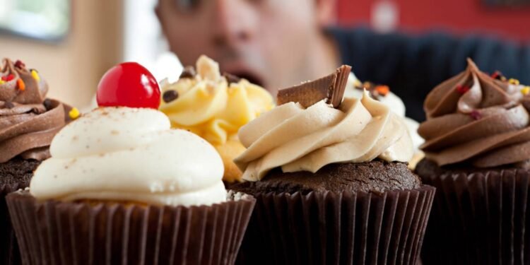 Homem impressionado com cupcakes em sua frente