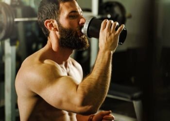 Homem tomando líquido para treinar na academia