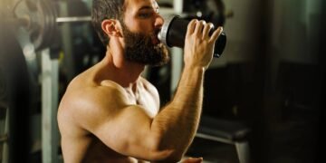 Homem tomando líquido para treinar na academia