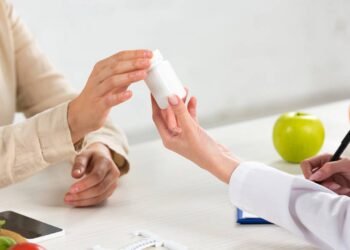 Médica prescrevendo e entregando cápsulas vitamínicas para paciente em consultório