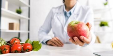 Médica segurando uma maçã em seu consultório