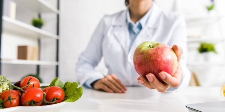 Médica segurando uma maçã em seu consultório