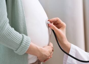 Médico ouvindo barriga de mulher grávida