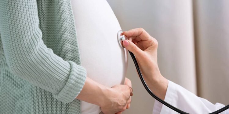 Médico ouvindo barriga de mulher grávida