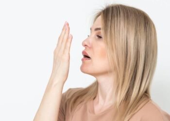 Mulher checando o próprio hálito com as mãos