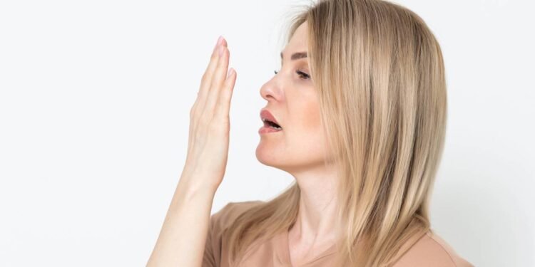 Mulher checando o próprio hálito com as mãos