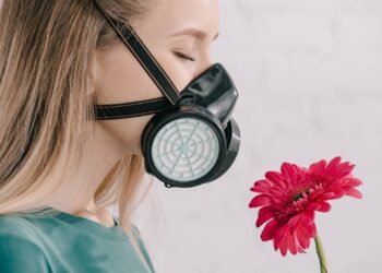 Mulher cheirando flores pela máscara respiratória