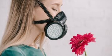 Mulher cheirando flores pela máscara respiratória