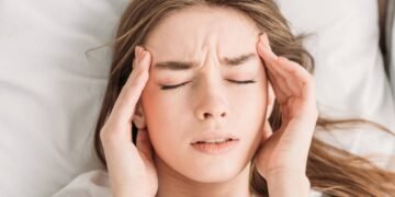 Mulher com os olhos fechados sofrendo com dores de cabeça