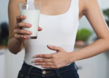 Mulher tendo dores de estômago após beber copo com leite
