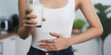 Mulher tendo dores de estômago após beber copo com leite