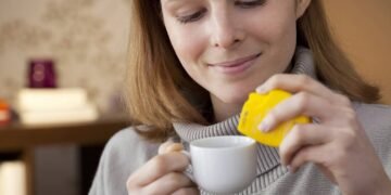 Mulher usando adoçante na bebida direto na xícara