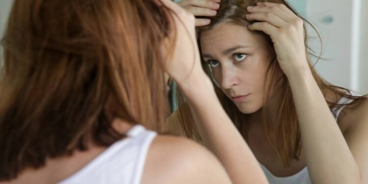 Um sinal muito comum é perceber a risca mais larga e o couro cabeludo aparecendo mais, mesmo com tudo ainda coberto por fios. - Créditos: depositphotos.com / triocean2011