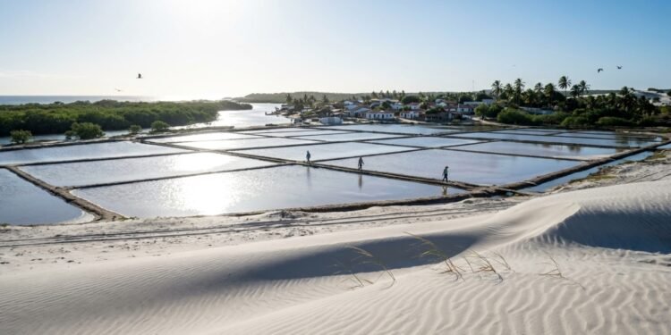 A 160 km da capital, o vilarejo sem carros e com travessia de 10 minutos, onde 2.104 moradores vivem entre dunas brancas e as maiores salinas do Brasil