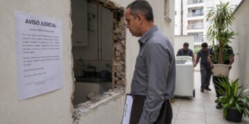 Dois vizinhos abriram uma porta pro pátio do prédio sem permissão e colocaram máquina de lavar e plantas: a Justiça INTERVEIO Transformar uma janela em porta para acessar o pátio do condomínio sem pedir licença? Não deu nada bem, amiga! Um caso em Sevilha virou alerta sobre o uso de áreas comuns em condomínios. Bora entender seus direitos e evitar confusão com a vizinhança? O que aconteceu no caso da porta aberta em área comum do condomínio? Dois proprietários de um edifício em Sevilha converteram uma janela em porta para ter acesso direto a um pátio comum, sem pedir autorização da comunidade de condôminos. Além disso, instalaram máquina de lavar e vasos de plantas no espaço coletivo, segundo decisão divulgada pelo Poder Judicial da Espanha. O Tribunal Provincial de Sevilha foi categórico: as obras eram ilegais. Por isso, determinou a remoção de todos os objetos e a restauração completa da área ao estado original. Esse caso virou referência sobre uso de áreas comuns em condomínios! O que nunca se deve fazer em áreas comuns do condomínio? Converter janelas em portas ou abrir novos acessos sem aprovação formal da comunidade. Instalar eletrodomésticos ou móveis pessoais em pátios, corredores ou halls coletivos. Ocupar espaços comuns com vasos, bicicletas ou objetos de uso exclusivo por tempo prolongado. Realizar qualquer obra que altere elementos estruturais sem projeto e autorização em assembleia. Basear-se no comportamento de outro vizinho para justificar infrações próprias. Não rola!