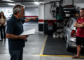 Homem mais velho aponta para uma vaga de garagem enquanto segura documentos, diante de um carro estacionado e de outro morador com os braços cruzados.