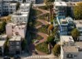Vista aérea da Lombard Street em São Francisco, com carros percorrendo oito curvas fechadas entre jardins e edifícios residenciais.