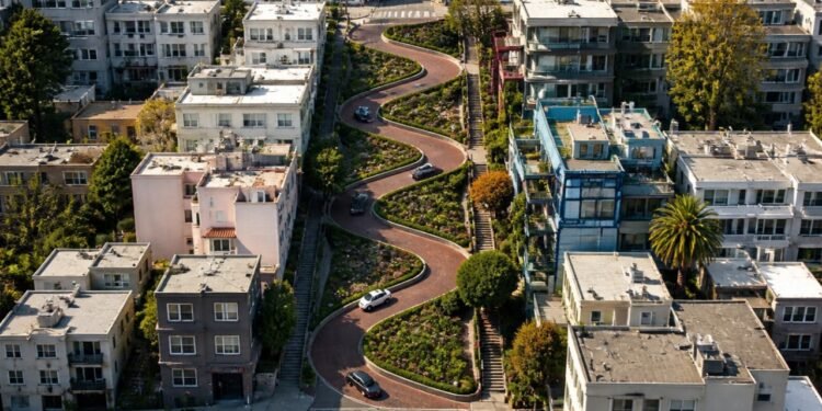 Vista aérea da Lombard Street em São Francisco, com carros percorrendo oito curvas fechadas entre jardins e edifícios residenciais.
