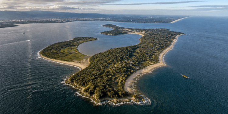 Vista aérea da Ilha do Mel, com mata densa, praias, enseadas, lagoas e o oceano ao redor.