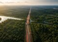 Vista aérea da BR-319 atravessando uma extensa área de floresta amazônica, com rios e trechos alagados ao redor da estrada.