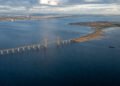 Vista aérea da Ponte de Øresund atravessando o mar até uma ilha artificial, com trecho estaiado, navio e áreas costeiras ao fundo.
